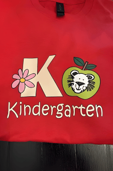 Individuell bedrucktes rotes Kindergarten-Shirt mit buntem Logo, Blumen-Motiv und Schriftzug, erstellt mit einem langlebigen DTF Transfer.
