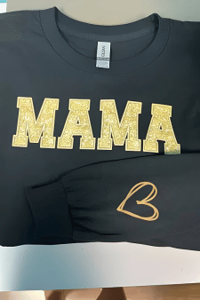 Schwarzer Hoodie mit 'MAMA' Schriftzug in goldener Glitzer-Optik und einem Herz auf dem Ärmel – hochwertiger DTF Transfer für personalisierte Geschenke.